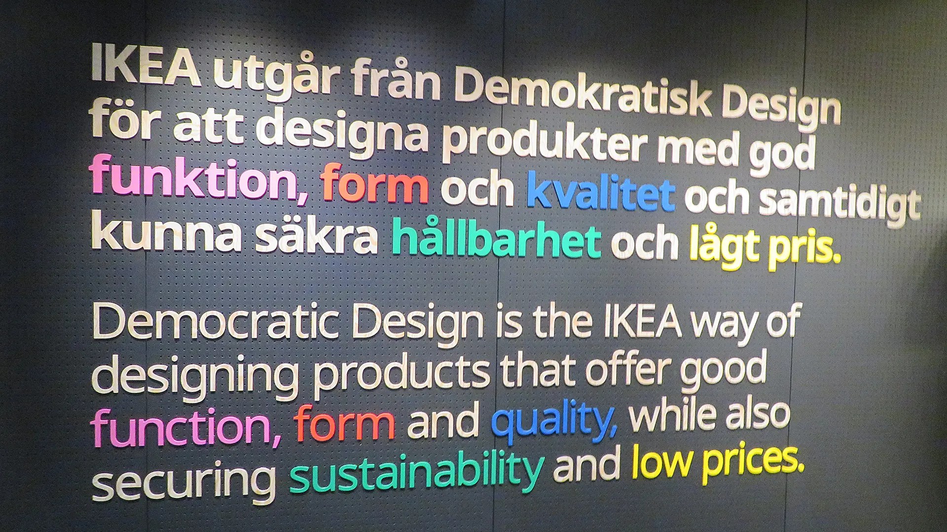 White text on a black wall describing IKEA's cornerstones of design. These words are written in different colors.