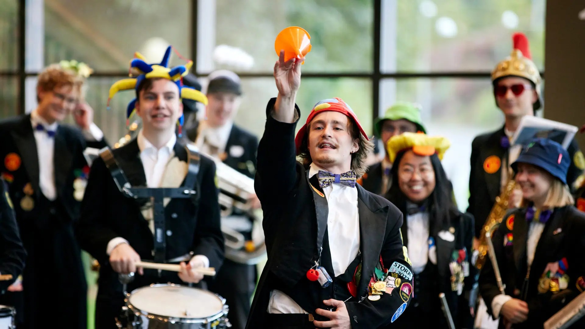 A playful orchestra member waves a red ball while the others play. They are dressed up and smiling happily.