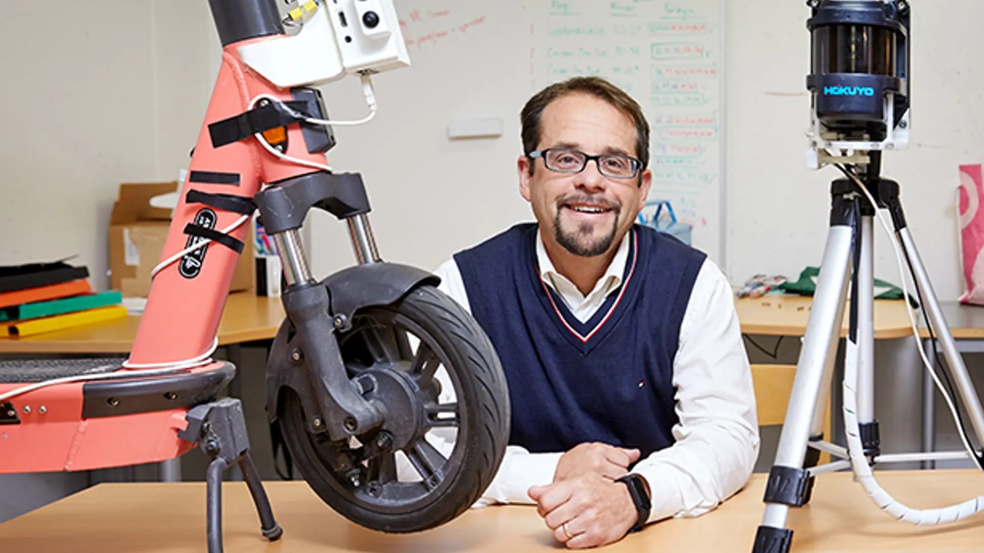 Marco Dozza, professor i trafiksäkerhet, sitter vid ett bord med en elsparkcykel och andra forskningsinstrument