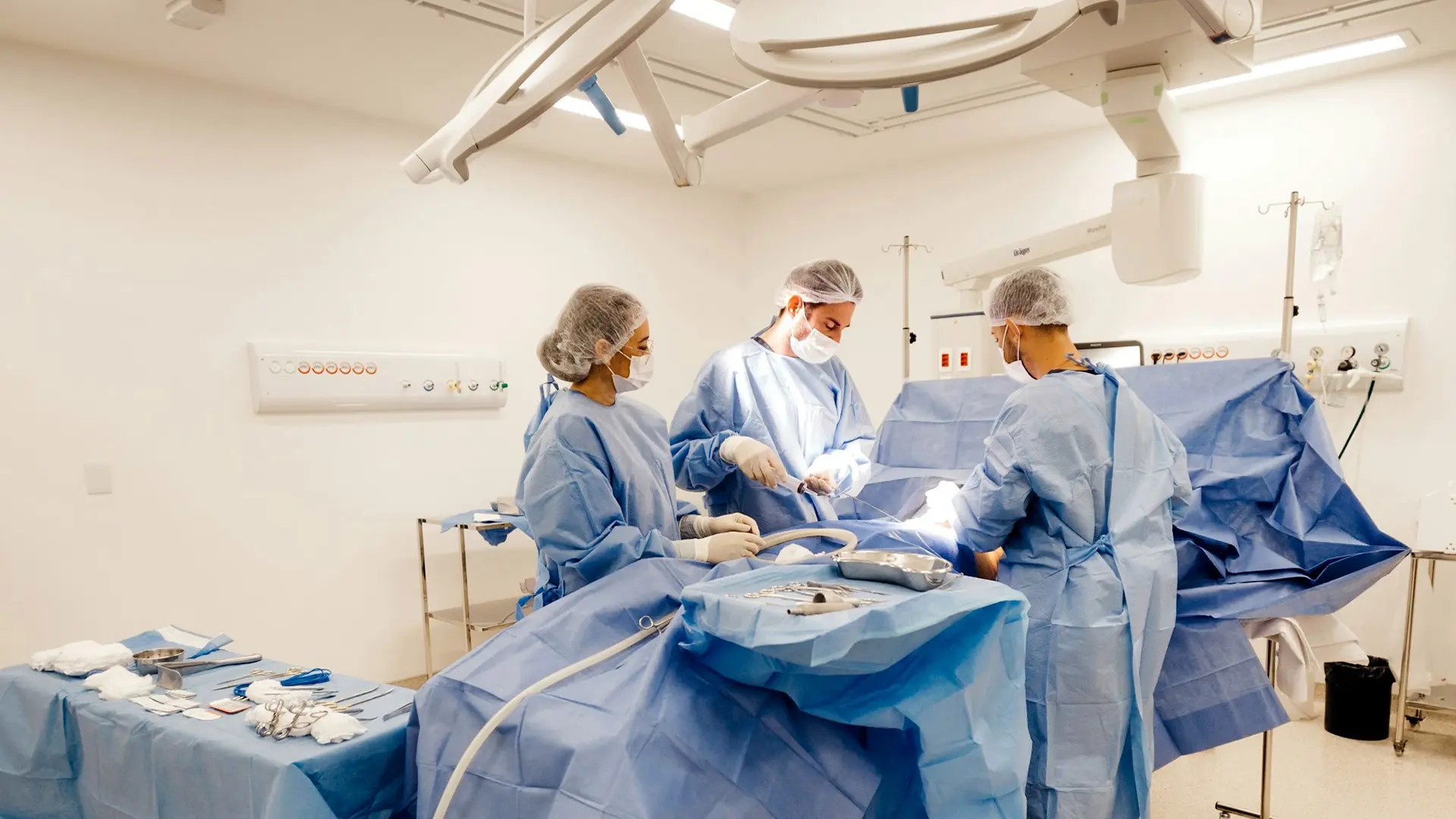 Hospital staff in blue clothes performing surgery on a patient. 