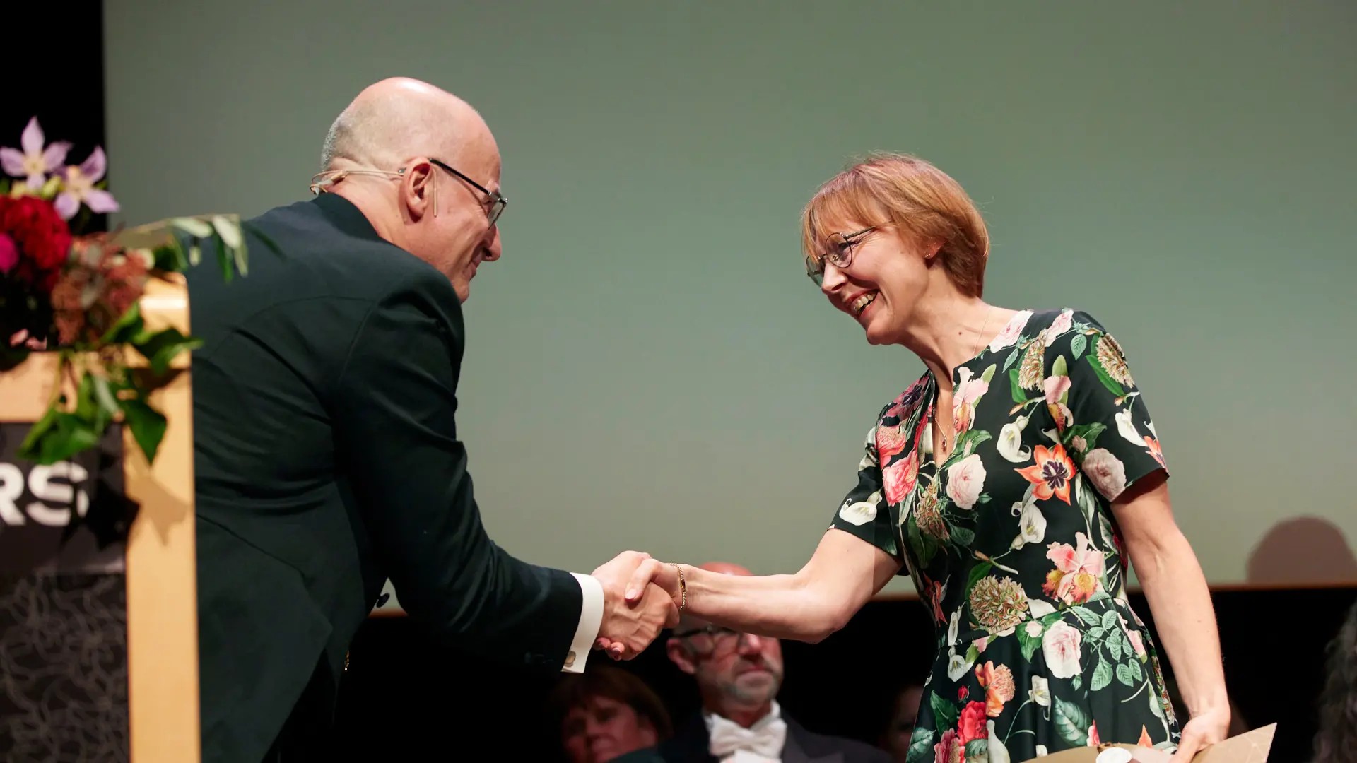 A woman shakes hands with a man.