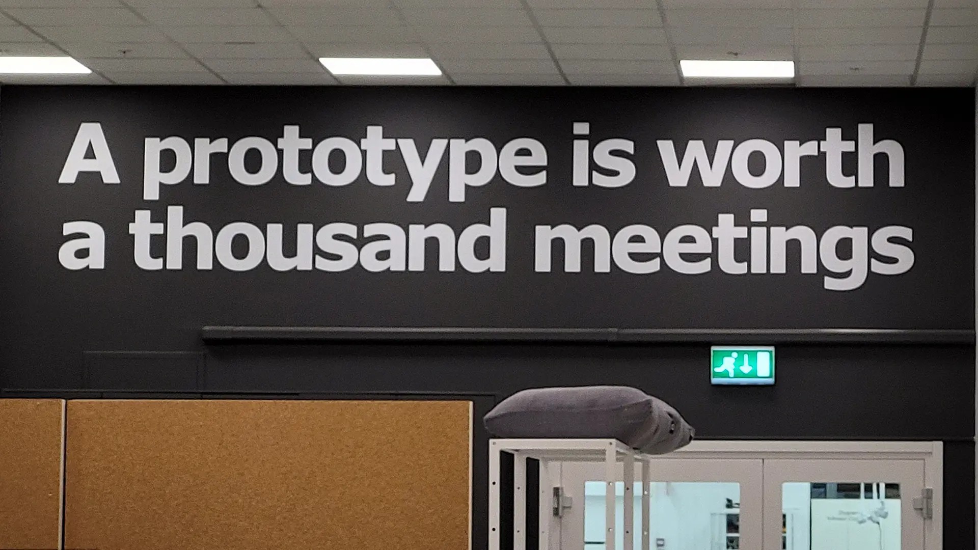 A sign with white text on a black background that says A prototype is worth a thousand meetings