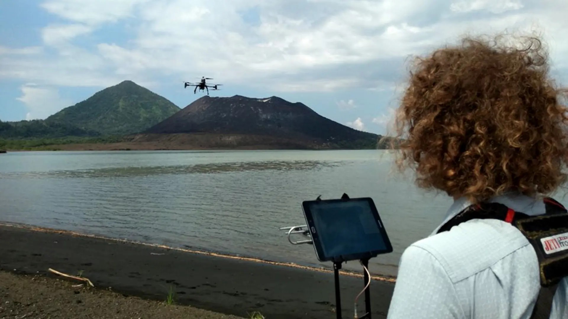 Drone operator guiding a drone towards a distant vulcano