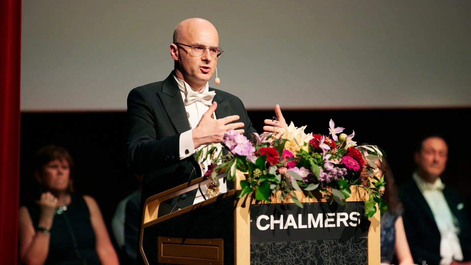 A man stands at a flower-adorned podium